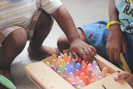 A child's hands and a box of chalk. 